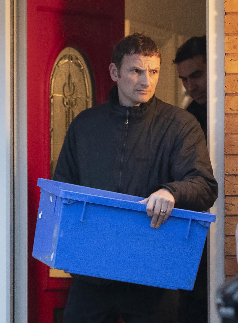 Police leave the home of Joanna and Thomas Maher with an evidence box at Wiltshire close in Warrington, Cheshire, Friday, Oct. 25, 2019, after a man and a woman, both aged 38 and from Warrington, have been arrested on suspicion of manslaughter and conspiracy to traffic people in connection with the 39 bodies found in a lorry in Essex on Wednesday. ( Jason Roberts/PA via AP)