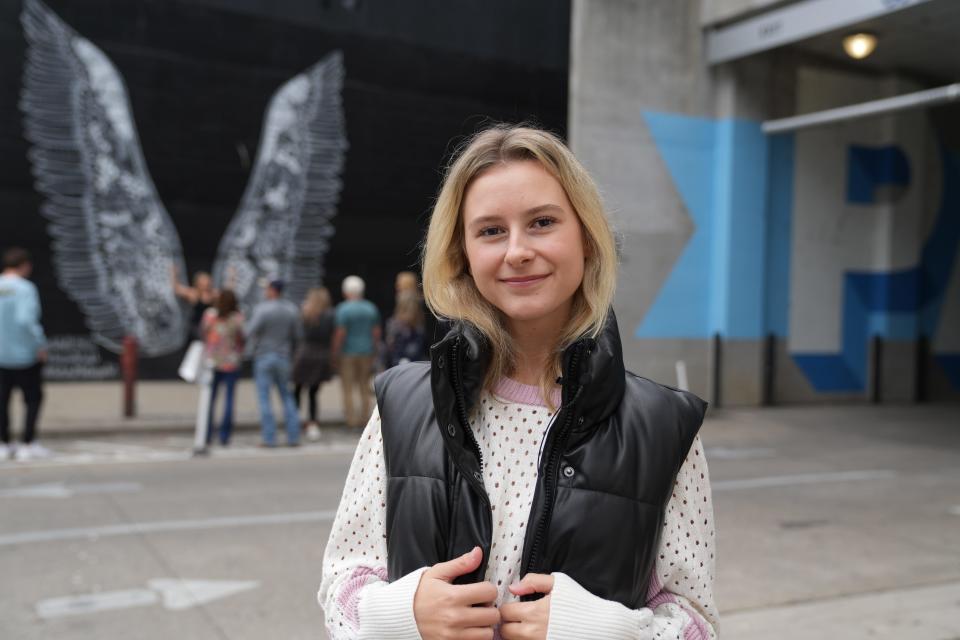 Olivia Levin, creator of the successful Instagram account @swiftiesforeternity, smiles in front of a Nashville mural.