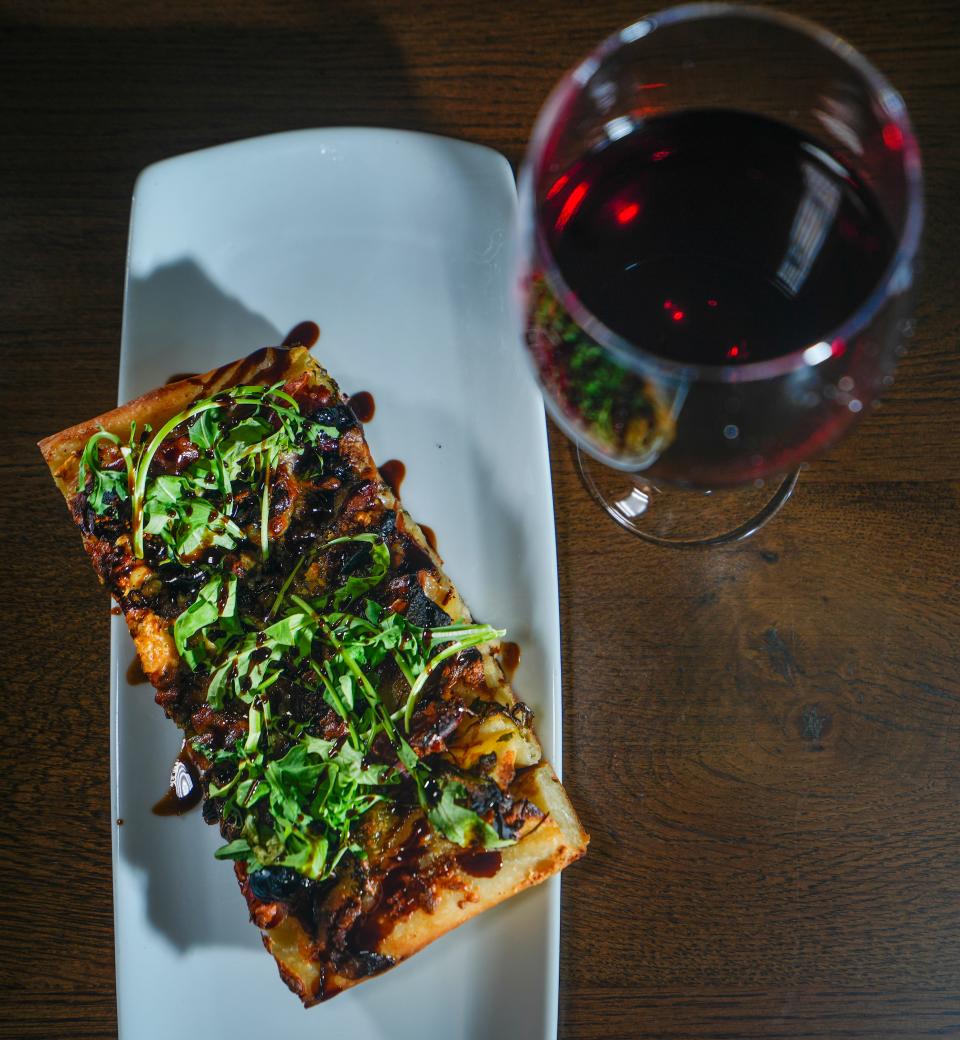 The Fig and Prosciutto Roman-style pizza reflects off a glass of Le Charmel Pinot Noir at Pizza Man at 2060 N. Humboldt Blvd. on July 7, 2023.