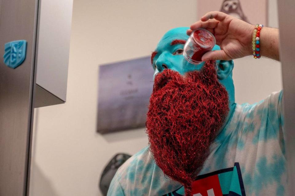 Richard Harper sprinkles red glitter onto his beard as he gets ready at home for an NWSL game between Kansas City Current and Bay FC on Saturday, April 20, 2024, in Kansas City.