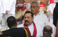 Sri Lanka’s former President Mahinda Rajapaksa, center, leaves with his younger brother, President Gotabaya Rajapaksa, behind, after being sworn in as the prime minister at Kelaniya Royal Buddhist temple in Colombo, Sri Lanka, Sunday, Aug. 9, 2020. (AP Photo/Eranga Jayawardena)