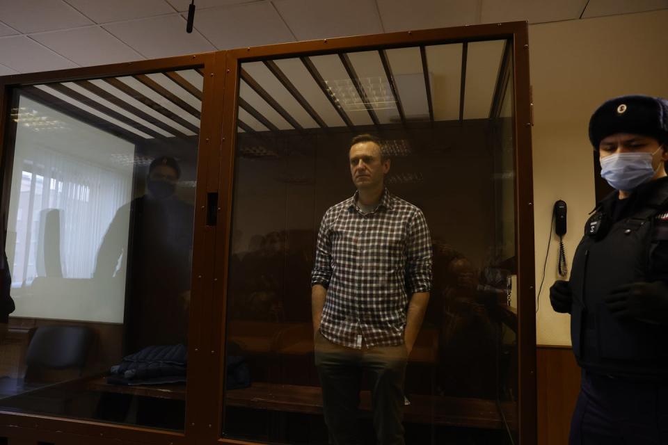 Alexei Navalny standing in court in a glass cell.