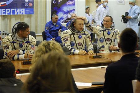 International Space Station crew members (L to R) U.S. astronaut Michael Hopkins, Russian cosmonauts Oleg Kotov and Sergey Ryazanskiy sit after their space suits check at the Baikonur cosmodrome September 25, 2013. REUTERS/Dmitry Lovetsky/Pool