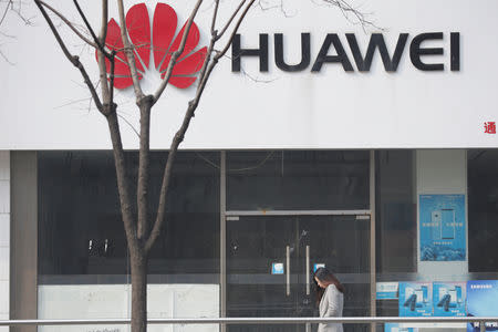 FILE PHOTO: A woman walks past a Huawei store in Beijing, China March 2, 2019. REUTERS/Jason Lee/File Photo