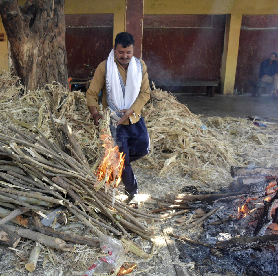 Uday Raj Pandey walks forward to light the funeral pyre of his son, who was killed in Friday's train accident, in Amritsar, India, Saturday, Oct. 20, 2018. A speeding train ran over a crowd watching fireworks during a religious festival in northern India on Friday evening, killing more than 50 people and injuring dozens more, police said. (AP Photo/Prabhjot Gill)