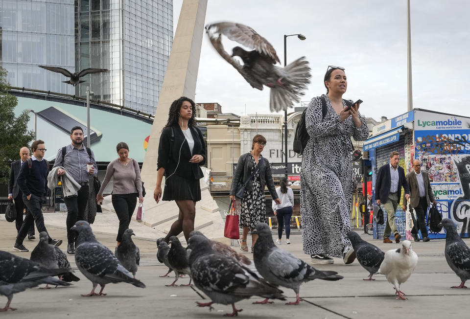 People passing pigeons to walk over the London Bridge to work in the City of London on Monday morning, Sept. 12, 2022. On morning television, the moment was singularly somber — the departure of the hearse bearing the flag-draped coffin of Queen Elizabeth II. But at the very same hour, as fans in shorts and Ray-Bans streamed into London's Oval stadium for a long-anticipated cricket match, you wouldn't have guessed the country was preparing for the most royal of funerals. (AP Photo/Martin Meissner)