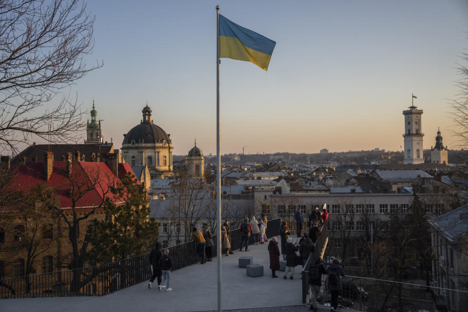 People gather in a vantage point that overlooks the city of Lviv, western Ukraine, Saturday, March 19, 2022. Lviv has been a refuge since the war began nearly a month ago, the last outpost before Poland and host to hundreds of thousands of Ukrainians streaming through or staying on. (AP Photo/Bernat Armangue)