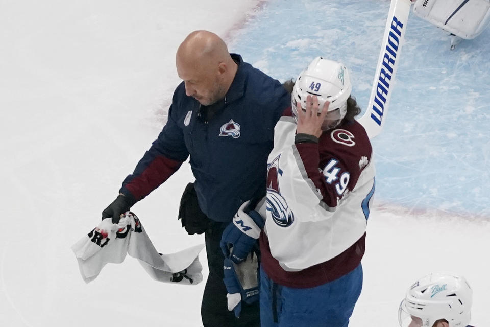 Colorado Avalanche's Samuel Girard (49) is helped off the ice by a trainer after being injured during the first period in Game 3 of an NHL hockey Stanley Cup second-round playoff series against the St. Louis Blues Saturday, May 21, 2022, in St. Louis. (AP Photo/Jeff Roberson)