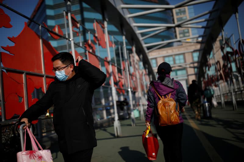 A man wearing a face mask pushes his luggage at a footbridge near Beijing Railway Station as the country is hit by an outbreak of the new coronavirus, in Beijing