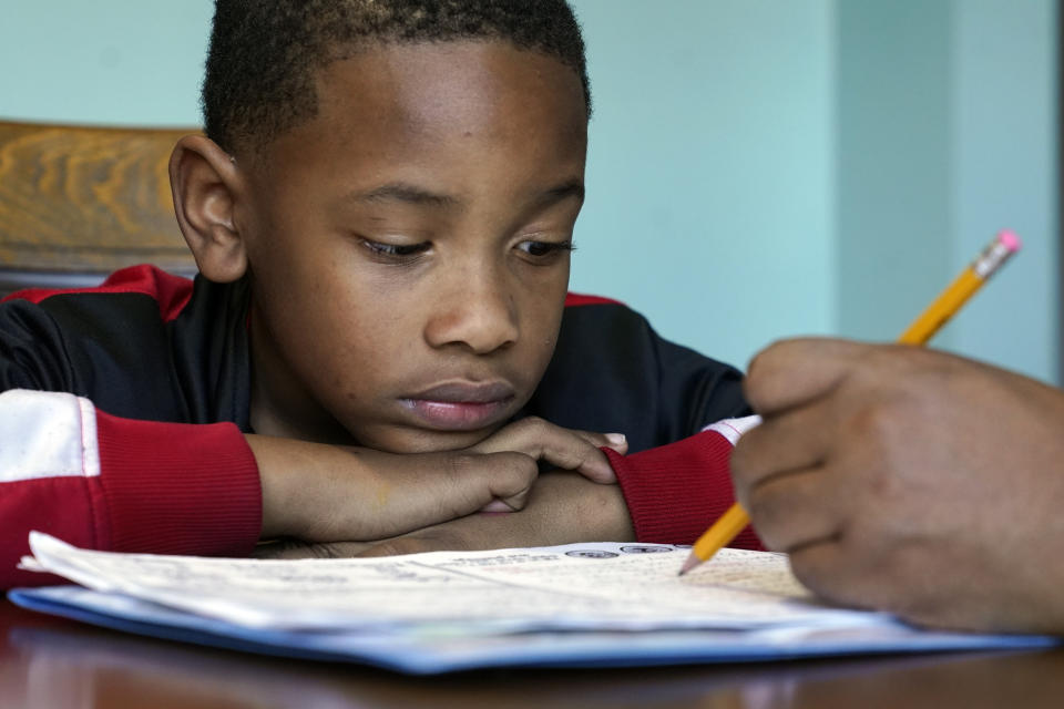 Christian Ensrud, 7, watches as his mother, Tamela Ensrud, help him with his homework at their home Monday, Nov. 21, 2022, in Nashville, Tenn. As parents try to help their children recover from several years of interrupted learning, some are struggling to get clear information explaining how their children are performing or a school plan to help them catch up on the learning they missed. (AP Photo/Mark Humphrey)