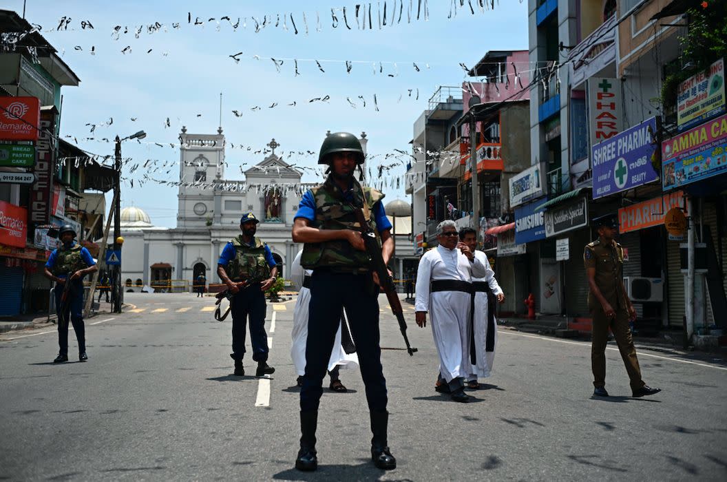 Priests walk on a blocked street as soldiers stand guard outside St. Anthony's Shrine in Colombo (Getty)