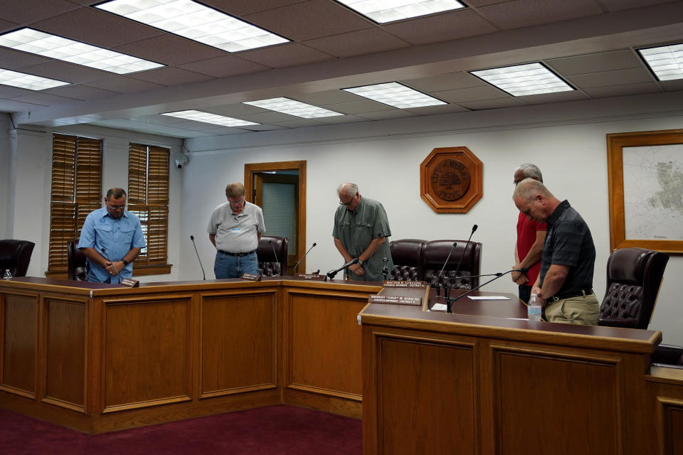 Uvalde Mayor Don McLaughlin, Jr., center, and members of the city council pray during a special emergency city council meeting, Tuesday, June 7, 2022, in Uvalde, Texas, to reissue the mayor's declaration of a local state of disaster due to the recent school shooting at Robb Elementary School. Two teachers and 19 students were killed. (AP Photo/Eric Gay)