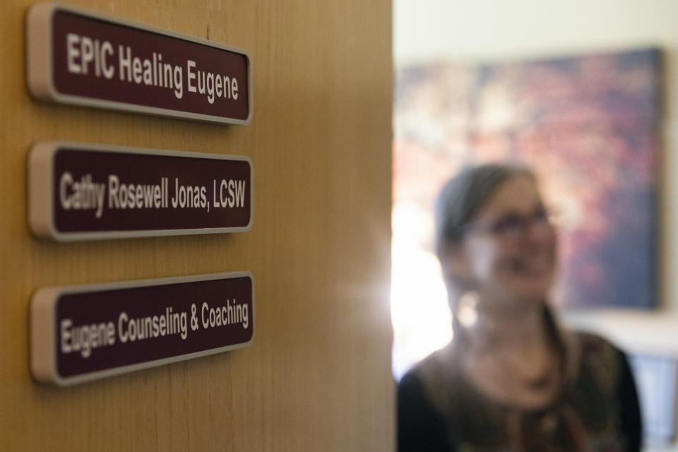 Cathy Jonas stands by a door at Epic Healing Eugene, Oregon’s first licensed psilocybin service center, Friday, Aug. 4, 2023, in Eugene, Ore. Epic Healing Eugene opened in June, marking the state’s unprecedented step in offering the mind-bending drug to the public. The center now has a waitlist of more than 3,000 names, including people with depression, PTSD or end-of-life dread. (AP Photo/Jenny Kane)