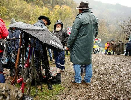 Participants use an umbrella to protect their infantry and assault rifles against rain during the traditional 'Ruetlischiessen' (Ruetli shooting) competition at the Ruetli meadow in central Switzerland November 6, 2013. REUTERS/Arnd Wiegmann/File Photo