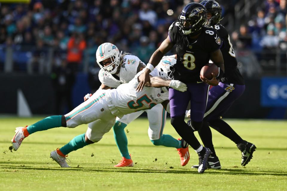 Baltimore Ravens quarterback Lamar Jackson (8) runs through Miami Dolphins linebacker David Long Jr. (51) tackle during the second half at M&T Bank Stadium.Baltimore Ravens defeated Miami Dolphins 56-19.