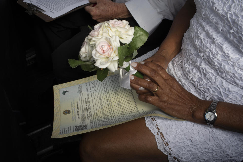 Una novia sostiene un ramo de flores durante su boda en el drive-thru de un registro en el vecindario de Santa Cruz, Río de Janeiro, Brasil, el 28 de mayo de 2020. Las parejas comenzaron a recurrir a esta forma poco convencional de contraer matrimonio en una notaría en Santa Cruz desde el inicio de la pandemia en el país. (AP Foto/Silvia Izquierdo)