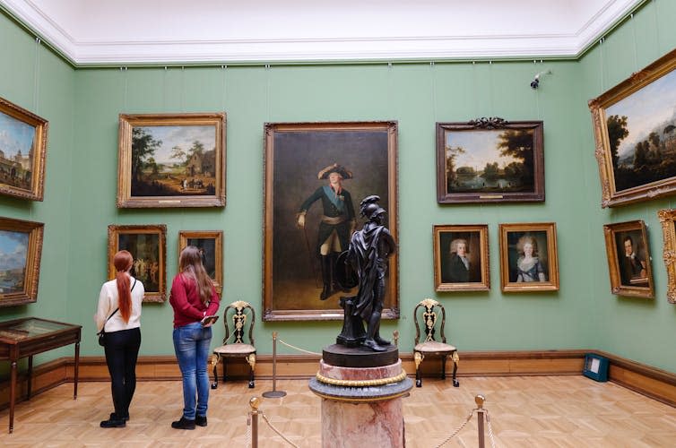 People looking at paintings in a gallery.