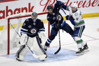 Winnipeg Jets' Dylan DeMelo (2) and Vancouver Canucks' Jayce Hawryluk (13) work for position beside Jets goaltender Connor Hellebuyck (37) during the second period of an NHL hockey game Tuesday, May 11, 2021, in Winnipeg, Manitoba. (Fred Greenslade/The Canadian Press via AP)