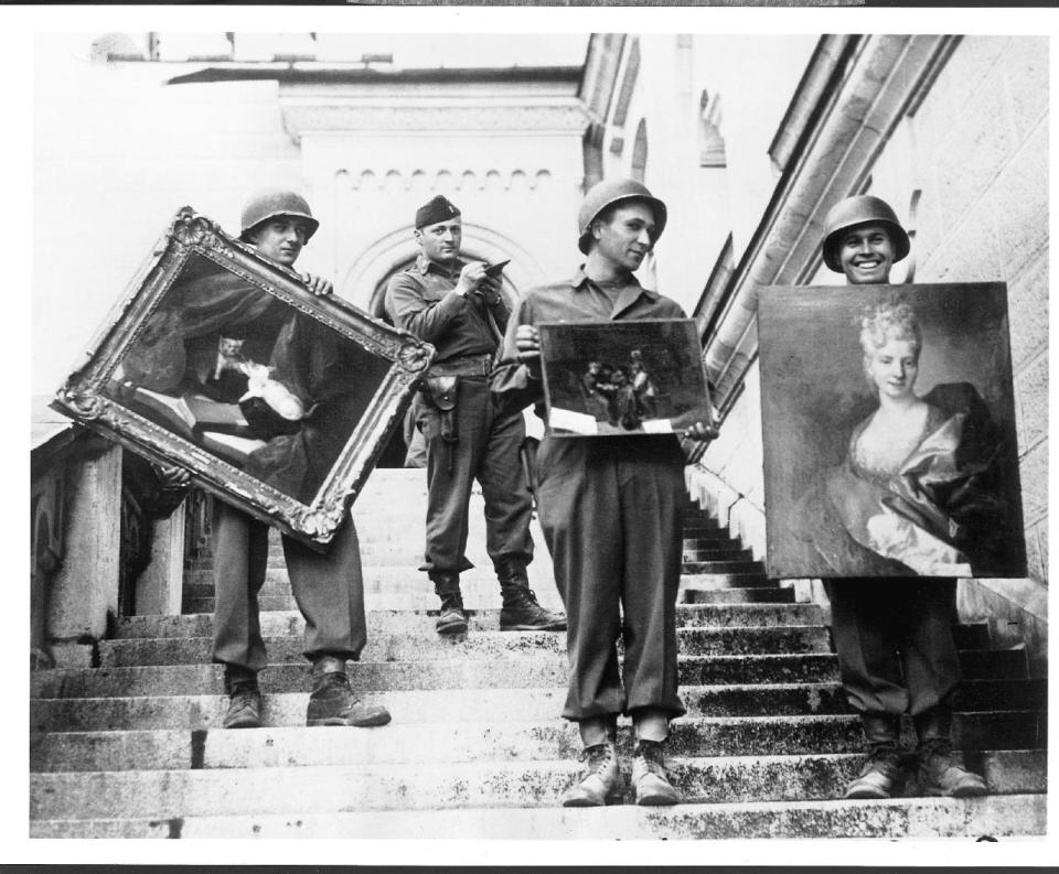 This photo provided by The Monuments Men Foundation for the Preservation of Art of Dallas, shows Monuments Man James Rorimer, with notepad, as he supervises American GI's hand-carrying paintings down the steps of the castle in Neuschwanstein, Germany in May of 1945. From a fairy tale-inspiring castle in the Bavarian Alps to a serene sculpture of Mary and Jesus by Michelangelo tucked away in a church in Belgium, sites and works of art across Europe can give travelers a glimpse at the heroic work done by those who worked to save cultural treasures during World War II.(AP Photo/National Archives and Records Administration)