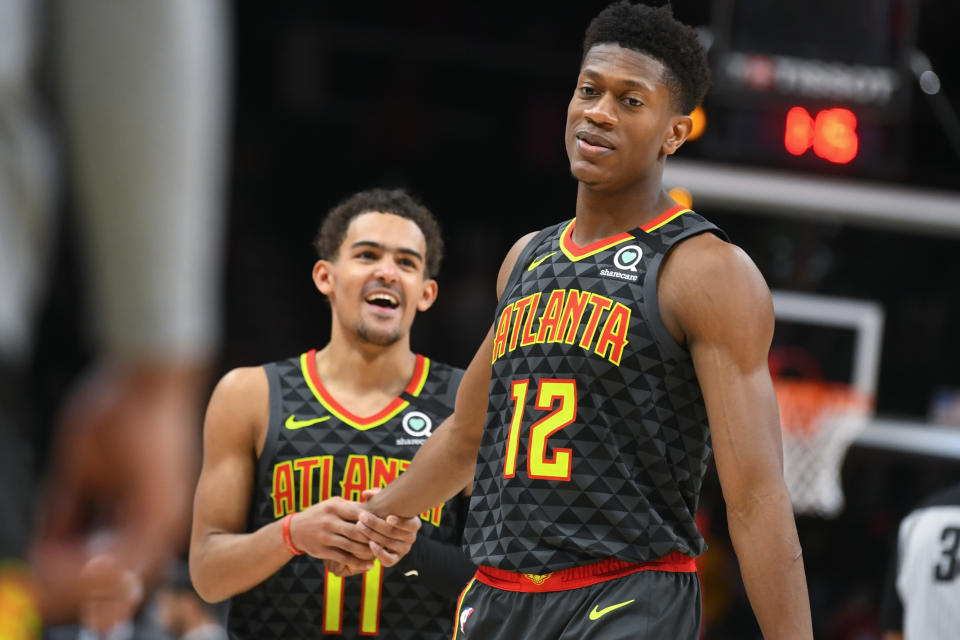 Atlanta Hawks forward De'Andre Hunter (12) is congratulated by guard Trae Young (11) as they come to the bench after Hunter hit three free throws to go ahead against the Charlotte Hornets during the second overtime in an NBA basketball game Monday, March 9, 2020, in Atlanta. (AP Photo/John Amis)