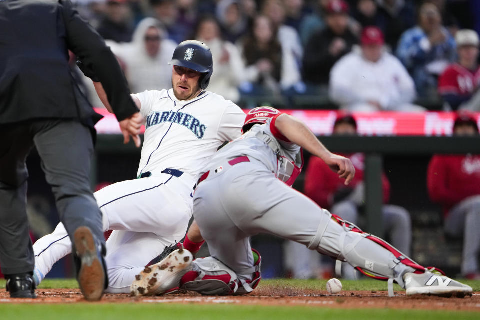 Seattle Mariners' Mitch Garver slides home to score on a double by Jonatan Clase, while Cincinnati Reds catcher Luke Maile drops the ball during the fourth inning of a baseball game Tuesday, April 16, 2024, in Seattle. (AP Photo/Lindsey Wasson)