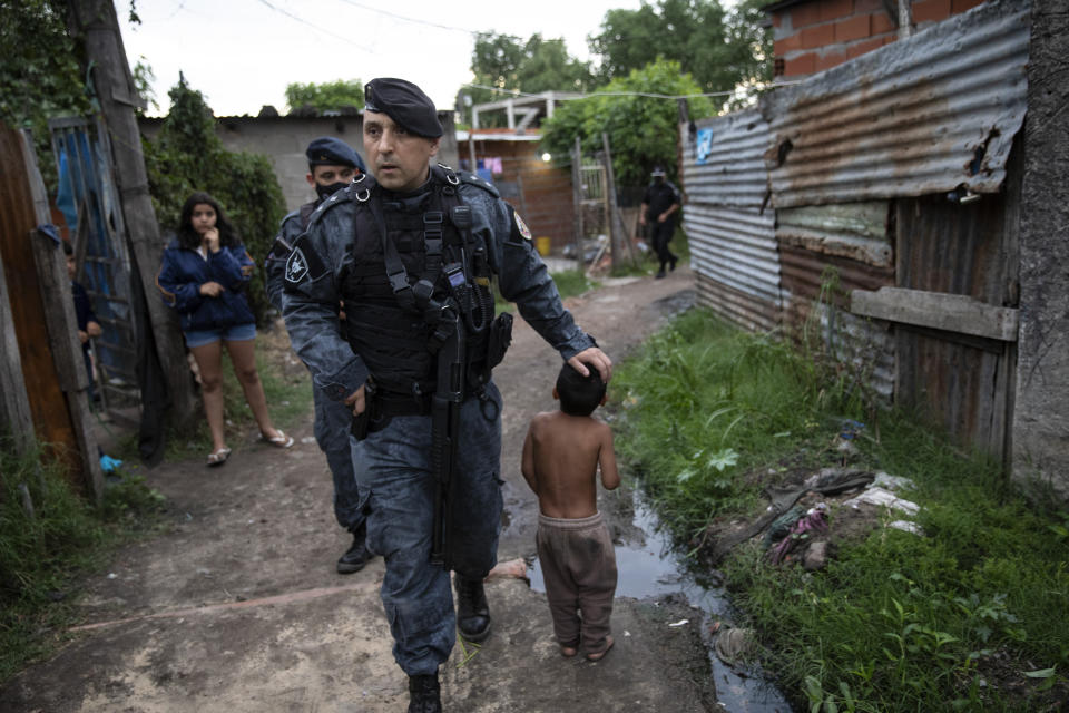 Special Forces Police officer Fabian Becerra greets a child while patrolling the poor neighborhood, Villa Banana, which has high rates of robbery and murder in Rosario, Argentina, Tuesday, Nov. 2, 2021. The city of some 1.3 million people has high levels of poverty and crime, where violence between gangs who seek to control turf and drug markets has helped fill its prisons. (AP Photo/Rodrigo Abd)
