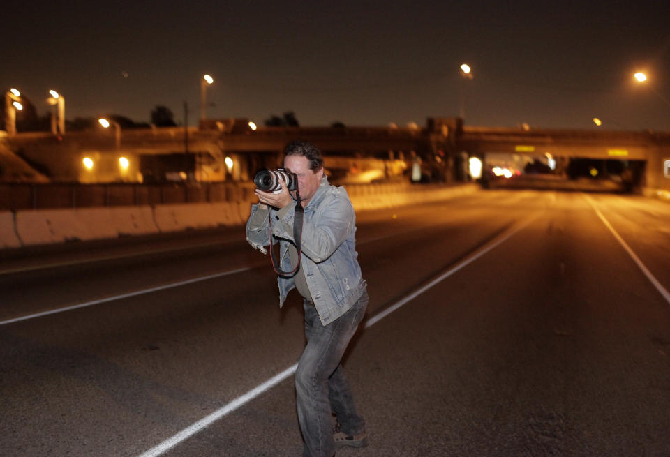 Blaine Houserman, of Toluca Lake, Calif., takes photos while standing in the middle of Interstate 405 during the freeway closure in Los Angeles, Saturday, July 16, 2011. When the sun rises above Los Angeles on Saturday, residents in this car-dependent, traffic-choked city will see a rare sight: a 10-mile (16-kilometer) stretch of one of America's busiest highways turned into a virtual ghost road. (AP Photo/Jae C. Hong)