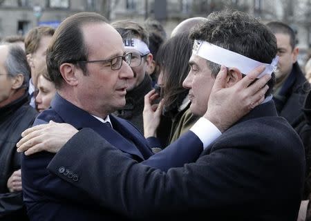 French President Francois Hollande (L) comforts French columnist for Charlie Hebdo Patrick Pelloux as they take part with family members and relatives in a solidarity march (Marche Republicaine) in the streets of Paris January 11, 2015. REUTERS/Philippe Wojazer