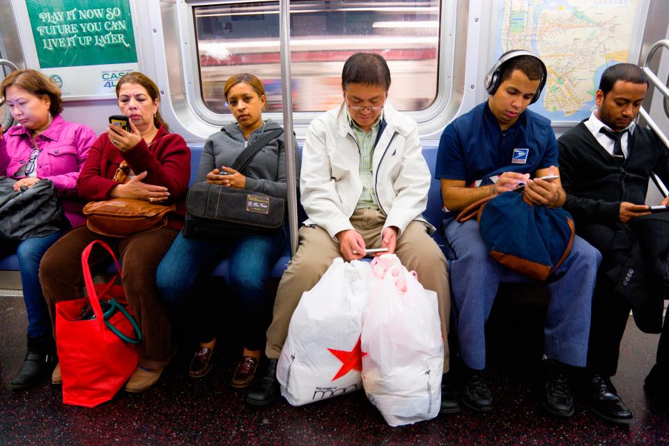 Commuters on the New York subway use their mobile phones.