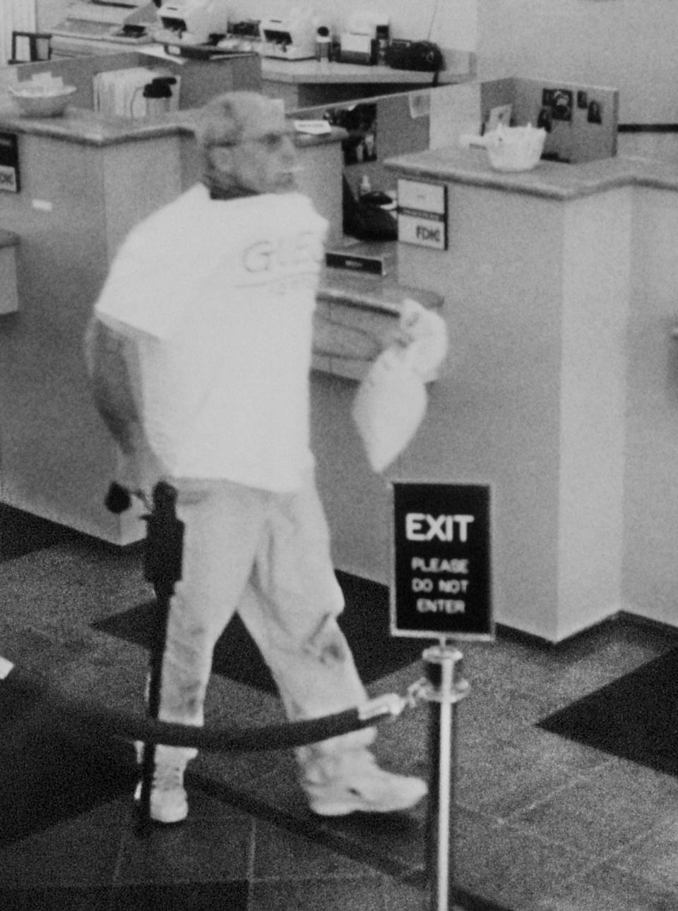 Brian Wells is seen leaving the PNC bank in Summit Towne Centre south of Erie on Aug. 28, 2003. He is carrying a cane gun and wearing a collar bomb, which is protruding from under his shirt. This image was taken after he received money from the teller. In his mouth is a lollipop that he picked up while waiting to approach the teller. Wells later died when the collar bomb went off.