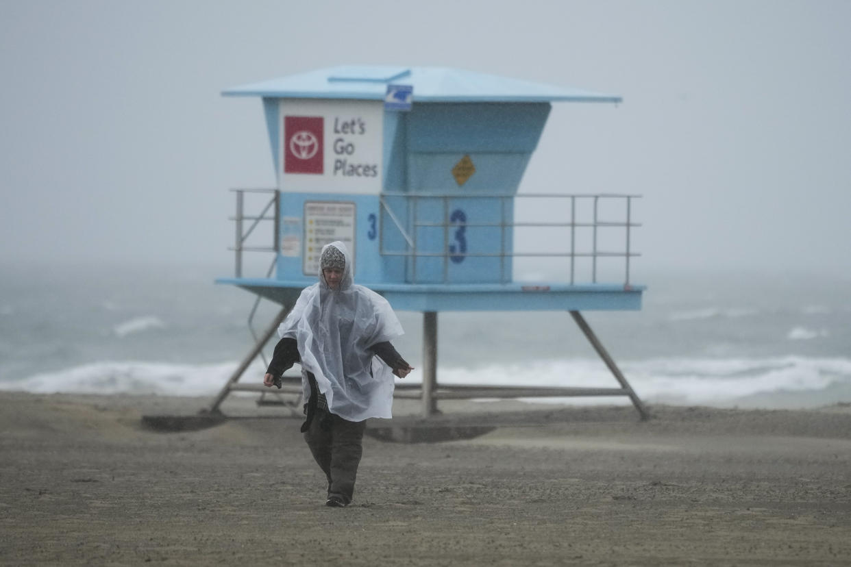 A beach comber walks along the beach on Friday, Feb. 24, 2023, in Huntington Beach, Calif. California and other parts of the West faced heavy snow and rain Friday from the latest winter storm to pound the U.S. (AP Photo/Ashley Landis)