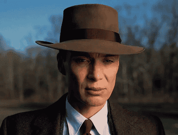 Cillian Murphy in a wide-brimmed hat stares with despair into nature