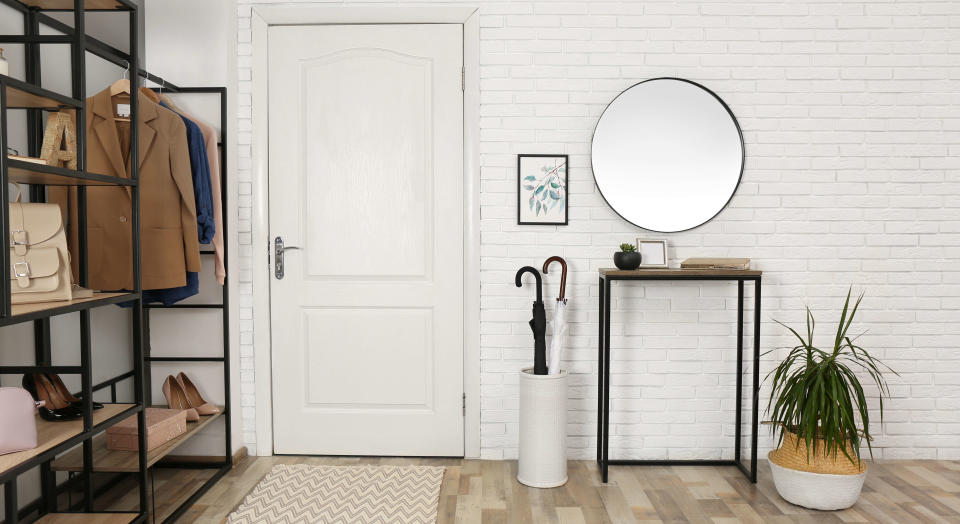 Console table and coat and shoe storage in a modern entryway, showing wooden flooring with a rug