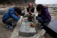Photo taken on April 11 shows a family praying by a grave in Ishinomaki, Miyagi prefecture. A year after whole neighbourhoods full of people were killed by the Japanese tsunami, rumours of ghosts swirl in Ishinomaki as the city struggles to come to terms with the awful tragedy