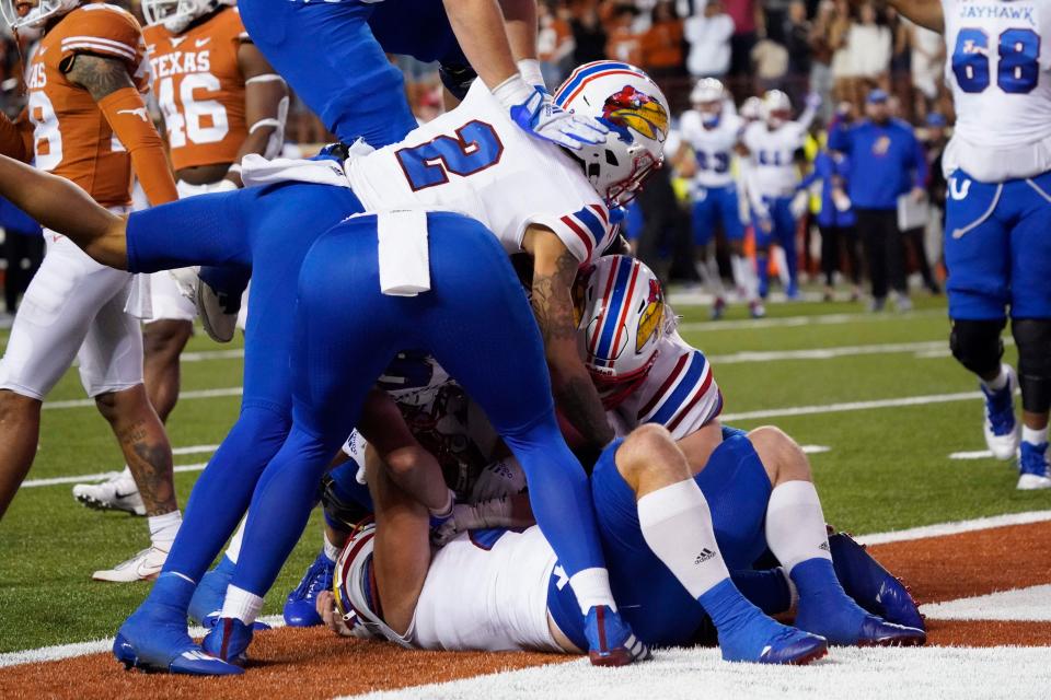 Kansas players pile on fullback Jared Casey (47) after Casey caught a pass for the game winning two-point conversion in overtime against Texas.