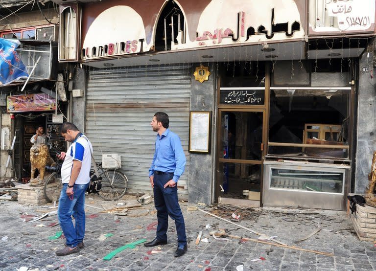 An image released by the Syrian Arab News Agency on June 11, 2013, shows Syrians standing amongst the damage in central Damascus following two explosions