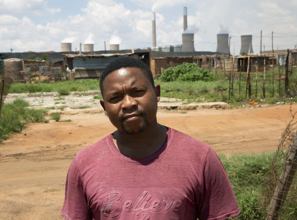 Selby Mahlalela poses for a photograph against the backdrop of the coal-powered Duvha power station, near Emalahleni (formerly Witbank) east of Johannesburg, Thursday, Nov. 17, 2022. Living in the shadow of one of South Africa’s largest coal-fired power stations, residents of Masakhane fear job losses if the facility is closed as the country moves to cleaner energy. (AP Photo/Denis Farrell)