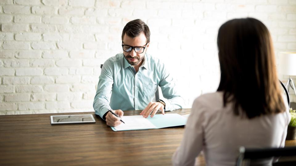 Male recruiter looking at a woman's resume during an interview for a new job position.