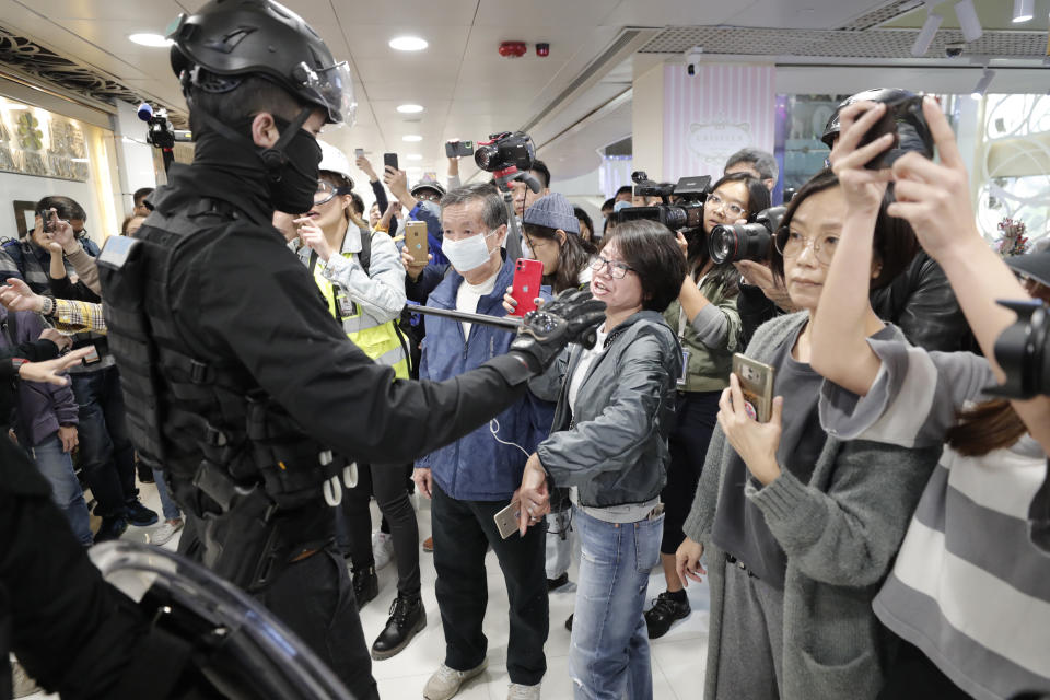 A riot policeman holds a baton during a demonstration at a shopping mall popular with traders from mainland China near the Chinese border in Hong Kong, Saturday, Dec. 28, 2019. Protesters shouting "Liberate Hong Kong!" marched through a shopping mall Saturday to demand that mainland Chinese traders leave the territory in a fresh weekend of anti-government tension. (AP Photo/Lee Jin-man)