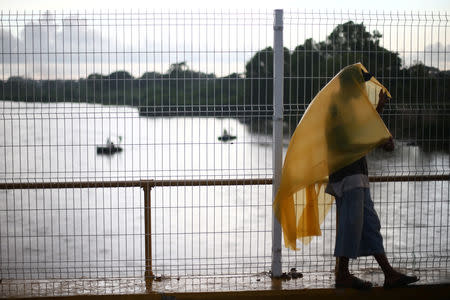 A Central American migrant, part of a caravan trying to reach the U.S; is pictured as he waits to open the gate on the bridge that connects Mexico and Guatemala in Ciudad Hidalgo, Mexico, October 21, 2018. REUTERS/Edgard Garrido