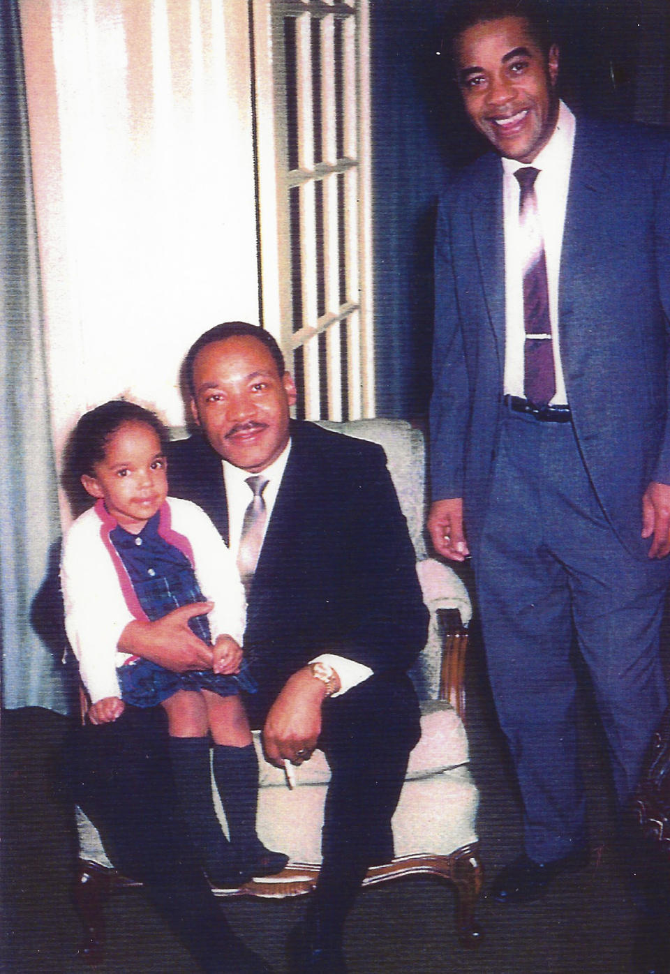 In an undated photo provided by Jawana Jackson, then- 4 year old Jawana sits on the Rev. Martin Luther King Jr's. knee next to her father Dr. Sullivan Jackson at the Jackson home in Selma, Ala. The house which was home base for the Rev. King in planning the Selma to Montgomery marches for Black voting rights, has been acquired by a historical museum in Michigan and will be moved to a site near Detroit for preservation. It will be dismantled starting this summer and trucked to The Henry Ford's Greenfield Village in Dearborn. The project is expected to take two to three years. (Jawana Jackson via AP)