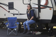 In this April 1, 2020, photo, Lisa Neuburger poses by the camper she is living in parked in her former in-laws' driveway in St. Paul Park, Minn. Neuburger is living in the camper after being exposed to the coronavirus as an ICU nurse. (AP Photo/Jim Mone)