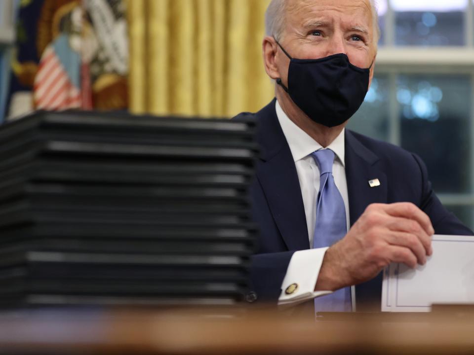 <p>Joe Biden prepares to sign a series of executive orders at the Resolute Desk in the Oval Office just hours after his inauguration on 20 January, 2021</p> (Getty Images)