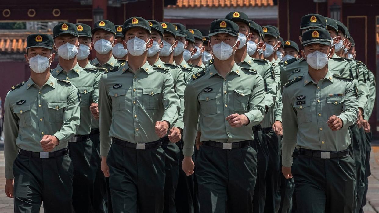 Chinese People's Liberation Army (PLA) soldiers wearing protective face masks march past the entrance to the Forbidden City in  2020.  (Roman Pilipey/AP - image credit)