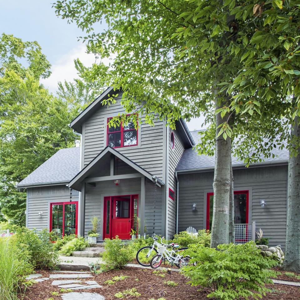 gray house with a red front door and window trim