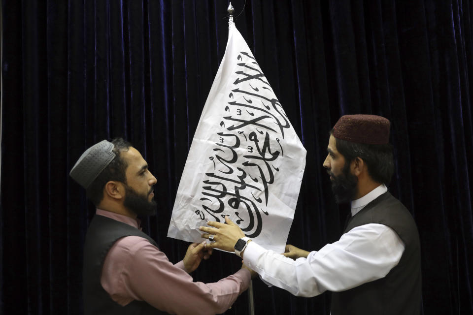 Taliban officials arrange a Taliban flag, before a press conference by Taliban spokesman Zabihullah Mujahid, at the Government Media Information Center, in Kabul, Afghanistan, Tuesday, Aug. 17, 2021. Mujahid vowed Tuesday that the Taliban would respect women's rights, forgive those who resisted them and ensure a secure Afghanistan as part of a publicity blitz aimed at convincing world powers and a fearful population that they have changed. (AP Photo/Rahmat Gul)