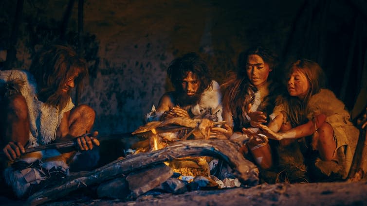Image of early humans sitting by the fire.