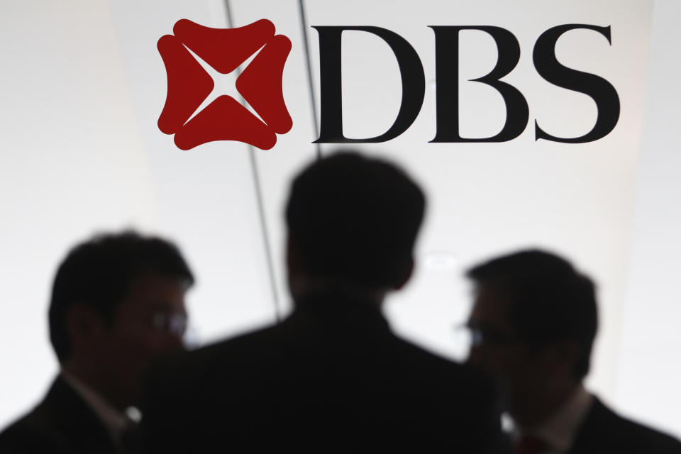 People talk next to a DBS logo at a DBS function in Singapore July 5, 2013. REUTERS/Edgar Su (SINGAPORE - Tags: BUSINESS LOGO)