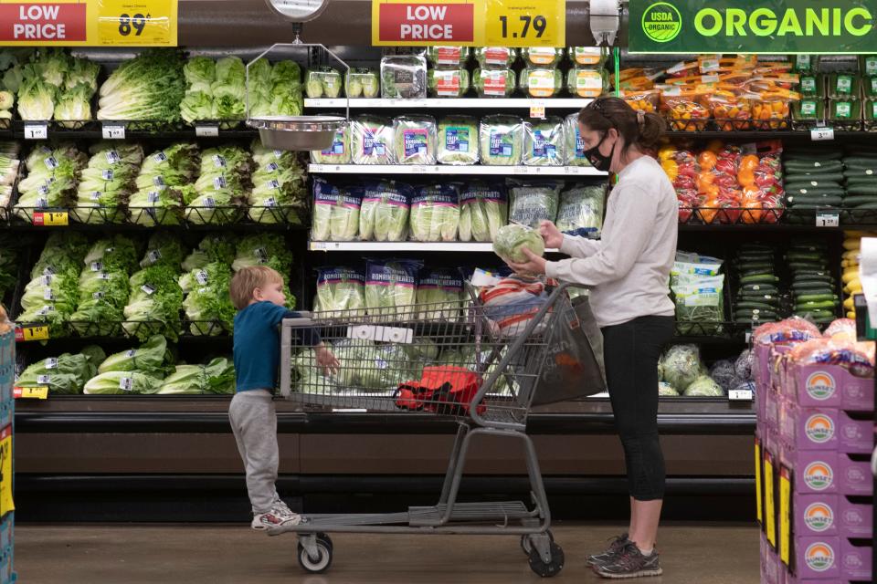 Emily Hidy and her 2-year-old son Ethan examine produce at Dillons in Topeka, Kan., Monday, Nov. 8, 2021. Hidy, who moved from Iowa and has three boys, says she thought it is strange that Kansas taxes their food unlike Iowa and other states she's visited.