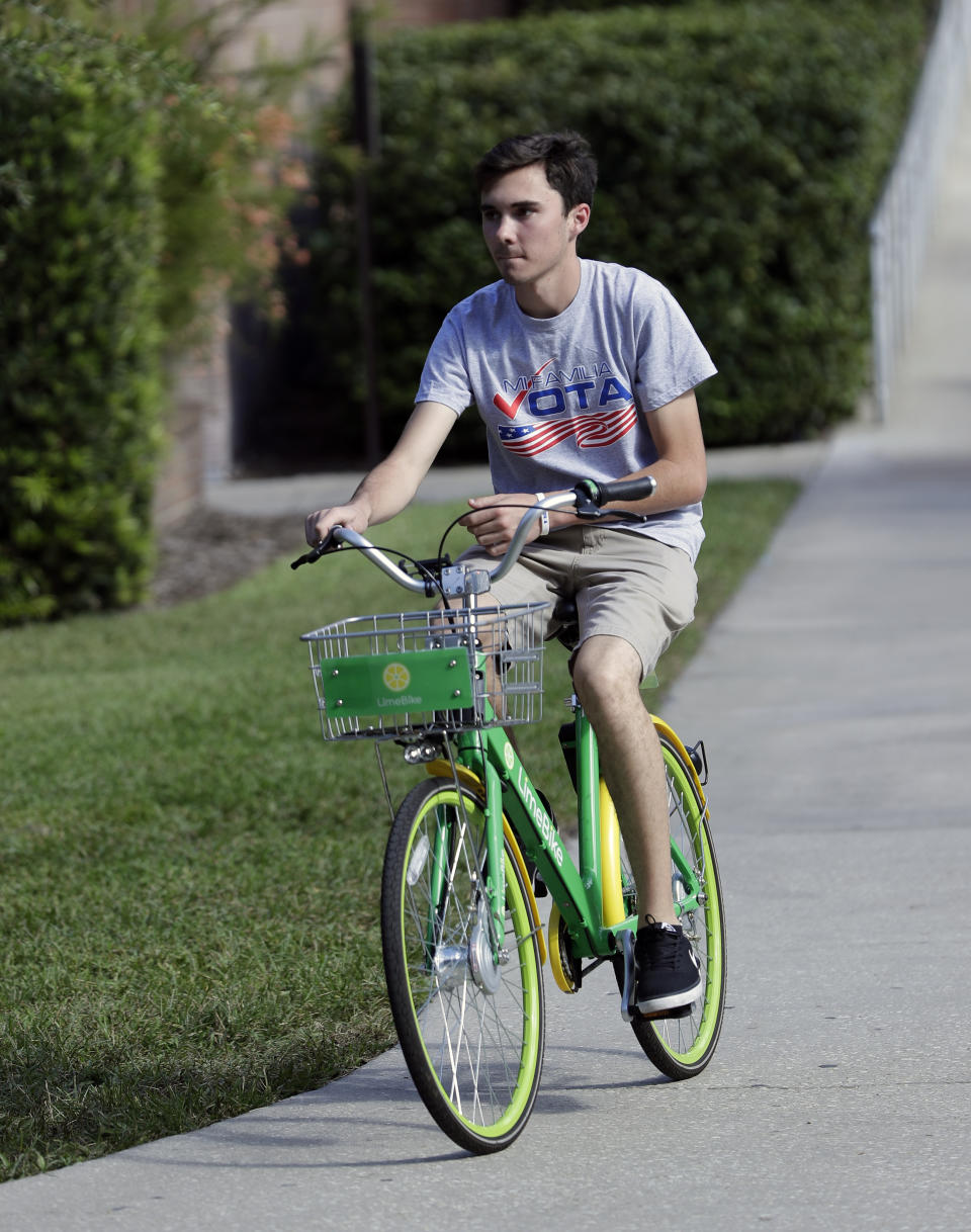 In this Wednesday, Oct. 31, 2018 photo, David Hogg, a student who survived the Stoneman Douglas High School shooting rides a bike on the campus of the University of Central Florida encouraging students to vote during a Vote for Our Lives event at the University of Central Florida in Orlando, Fla. Nine months after 17 classmates and teachers were gunned down at their Florida school, Parkland students are finally facing the moment they’ve been leading up to with marches, school walkouts and voter-registration events throughout the country: their first Election Day. (AP Photo/John Raoux)